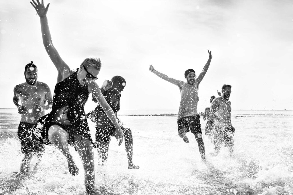 Amigos saltando sobre las olas del mar